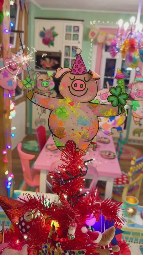 Umarmungs-Schweine mit einem bunten Schwein, das eine Glocke hält, umgeben von grünen Kleeblättern und Marienkäfern.